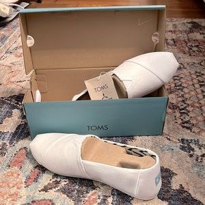 TOMS white canvas slip ons, never worn and in perfect condition.